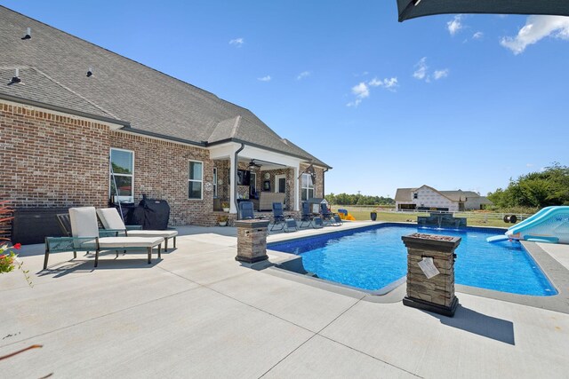 view of swimming pool featuring a patio area, a water slide, and pool water feature