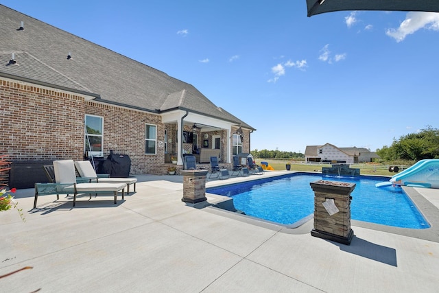 outdoor pool featuring a patio area, a ceiling fan, and a water slide