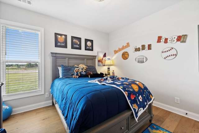 bedroom featuring visible vents, baseboards, and wood finished floors