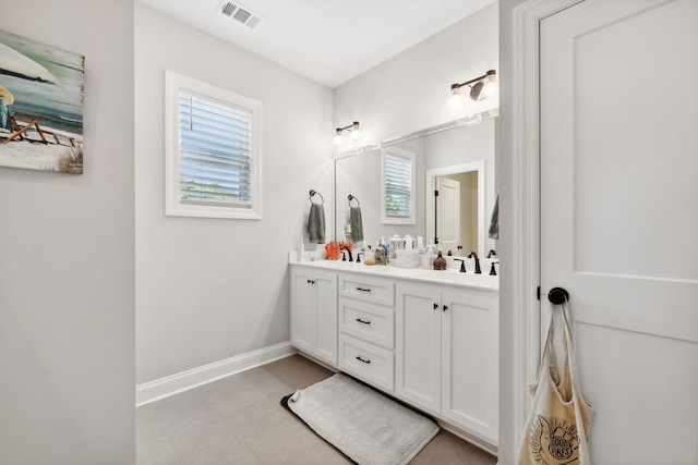 bathroom featuring double vanity, a sink, visible vents, and baseboards