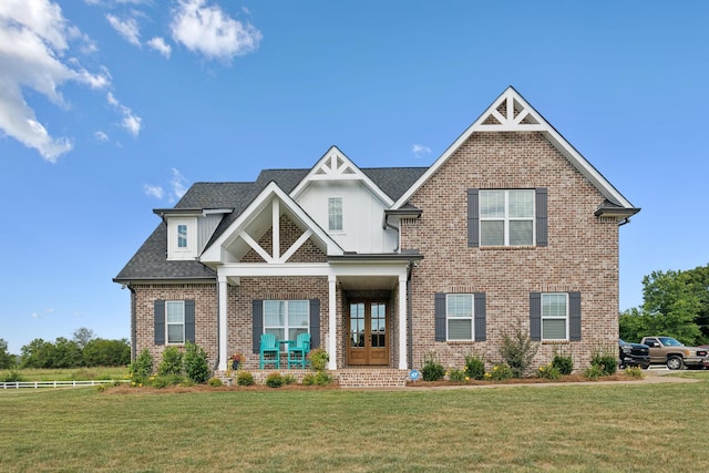 craftsman-style home with french doors, a front yard, brick siding, and a shingled roof