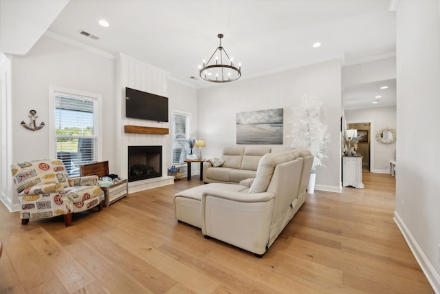 living room with light hardwood / wood-style floors, a large fireplace, a notable chandelier, and ornamental molding