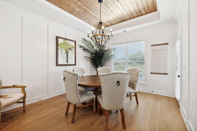 dining space featuring wooden ceiling, a raised ceiling, crown molding, and a decorative wall