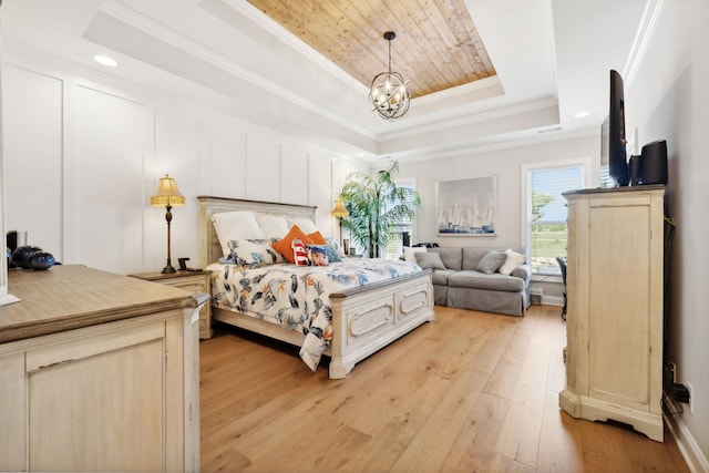 bedroom with a tray ceiling, light hardwood / wood-style floors, an inviting chandelier, and crown molding