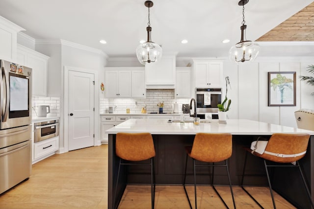 kitchen with light countertops, appliances with stainless steel finishes, white cabinets, and pendant lighting