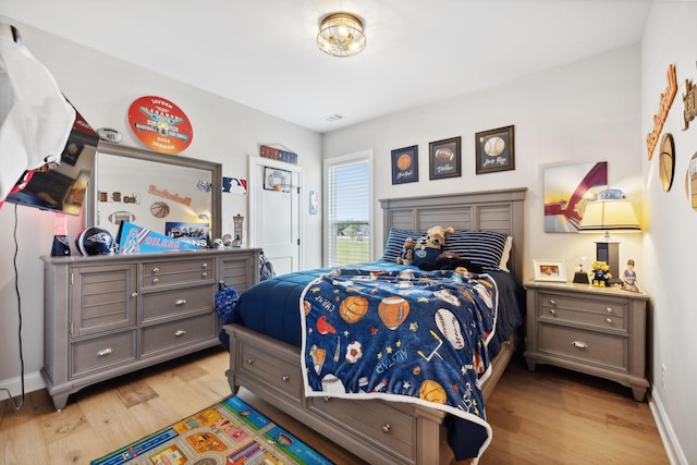 bedroom with light wood finished floors, visible vents, and baseboards