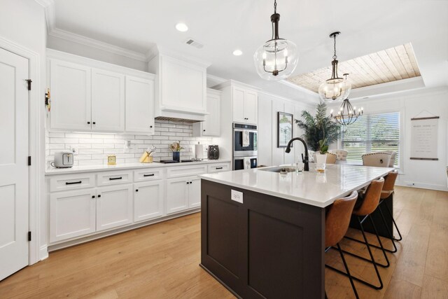 kitchen with light wood-type flooring, stainless steel double oven, and pendant lighting