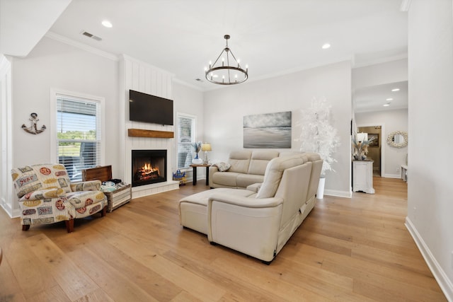 living room featuring light hardwood / wood-style flooring, a large fireplace, ornamental molding, and a chandelier