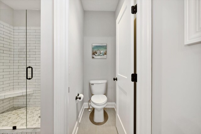 bathroom featuring tile patterned flooring, toilet, and an enclosed shower