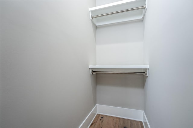 walk in closet with wood finished floors