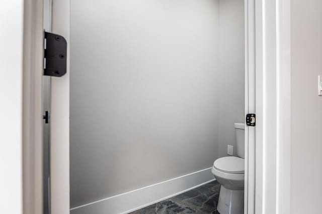 bathroom with toilet and baseboards