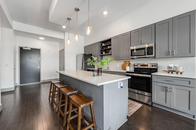 kitchen with tasteful backsplash, dark hardwood / wood-style floors, stainless steel appliances, and light stone counters