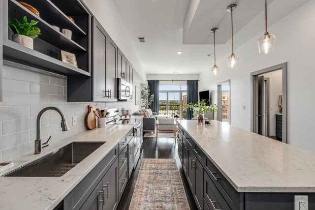 kitchen featuring dark hardwood / wood-style flooring, stainless steel appliances, light stone countertops, sink, and tasteful backsplash