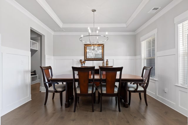 dining space featuring ornamental molding, a notable chandelier, a tray ceiling, and dark wood-type flooring