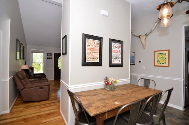 dining area with high vaulted ceiling and hardwood / wood-style flooring