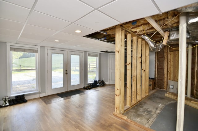 basement featuring wood-type flooring, french doors, and a paneled ceiling