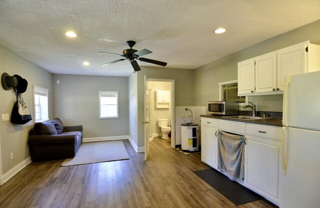 kitchen featuring ceiling fan, sink, white fridge, white cabinetry, and hardwood / wood-style flooring