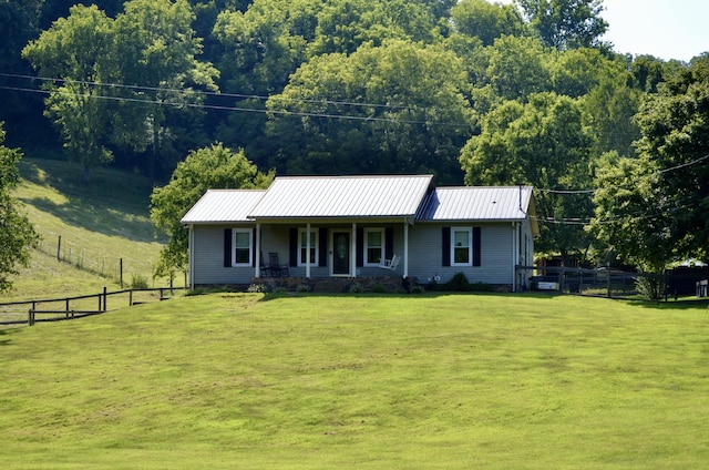 view of front facade featuring a porch, metal roof, fence, and a front lawn