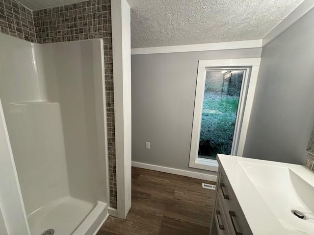 bathroom with vanity, hardwood / wood-style floors, a textured ceiling, and walk in shower