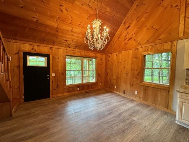 interior space with wooden ceiling, lofted ceiling, hardwood / wood-style flooring, and wooden walls