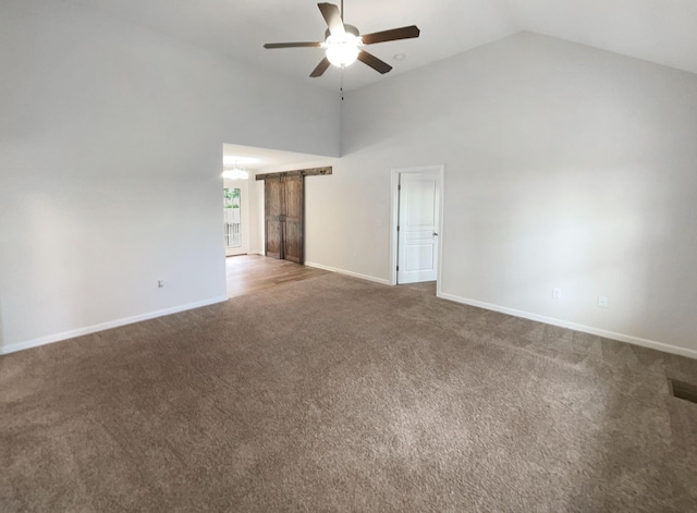 carpeted empty room with ceiling fan, a barn door, and high vaulted ceiling