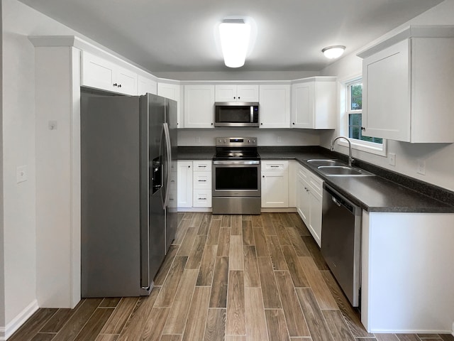 kitchen with sink, stainless steel appliances, hardwood / wood-style floors, and white cabinetry