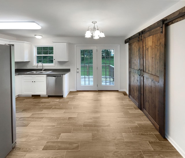 kitchen featuring sink, a barn door, white cabinets, and appliances with stainless steel finishes