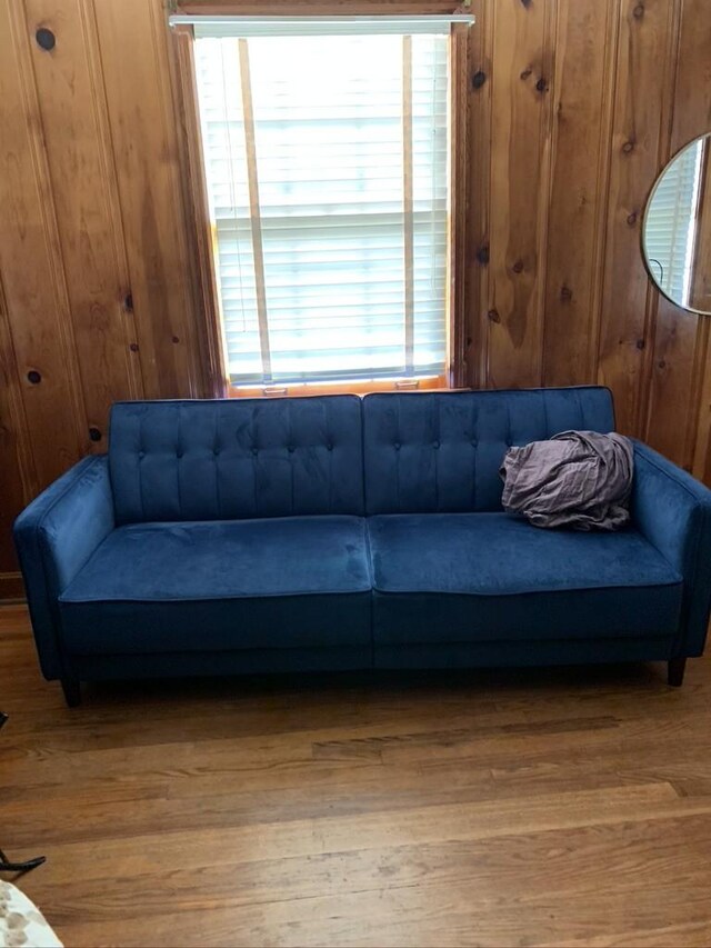 living room with a wealth of natural light, wooden walls, and hardwood / wood-style flooring