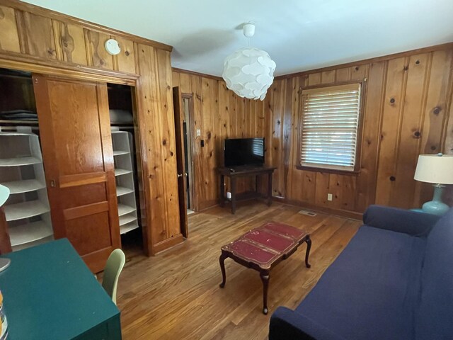 living room featuring light wood-type flooring and wood walls