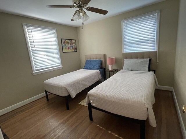 bedroom featuring ceiling fan, wood-type flooring, and multiple windows