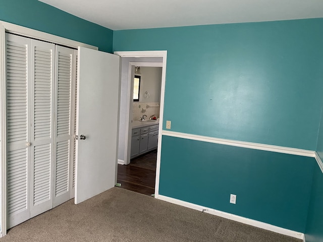 unfurnished bedroom with sink, carpet, and a closet