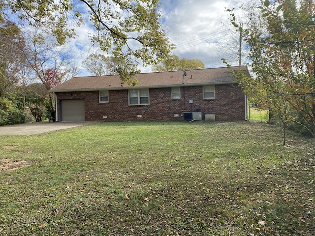 rear view of property featuring a garage, a yard, and central AC unit