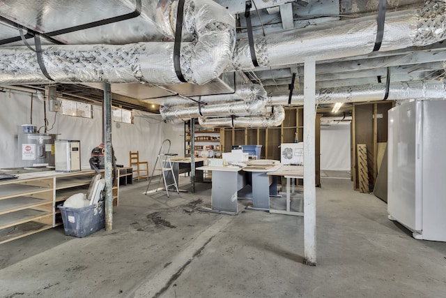 basement featuring electric water heater, washer / dryer, white refrigerator, and a workshop area