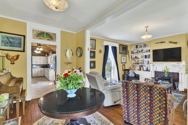 tiled living room featuring built in shelves, a fireplace, ceiling fan, and crown molding