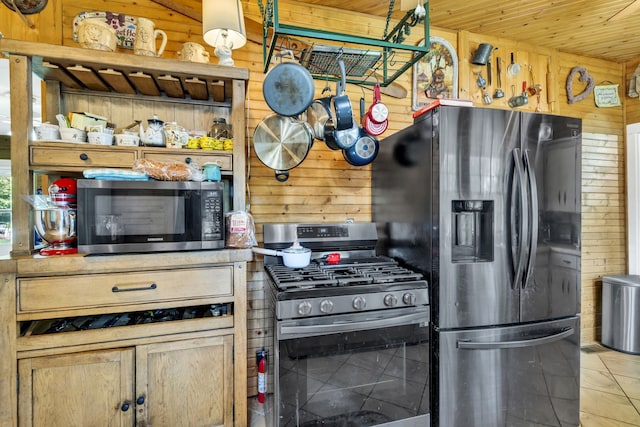 kitchen featuring stainless steel appliances, wood walls, wood ceiling, and light tile patterned floors