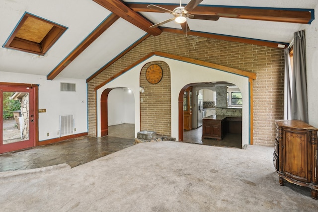 unfurnished living room with beam ceiling, carpet, and brick wall