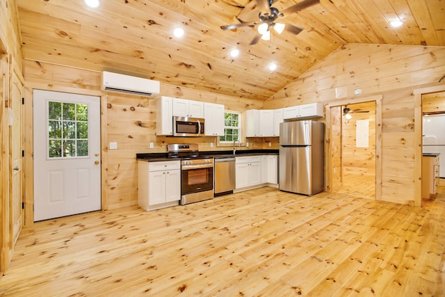 kitchen with a wall mounted AC, appliances with stainless steel finishes, white cabinetry, a healthy amount of sunlight, and ceiling fan