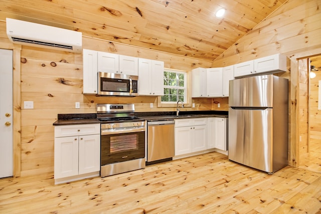 kitchen with a wall unit AC, stainless steel appliances, white cabinetry, and light hardwood / wood-style flooring