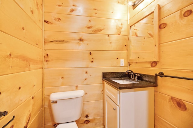 bathroom featuring vanity, toilet, and wood walls