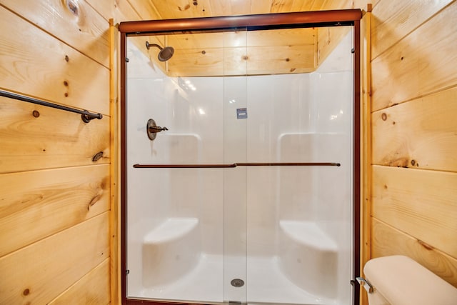 bathroom featuring toilet, wood walls, and a shower with door