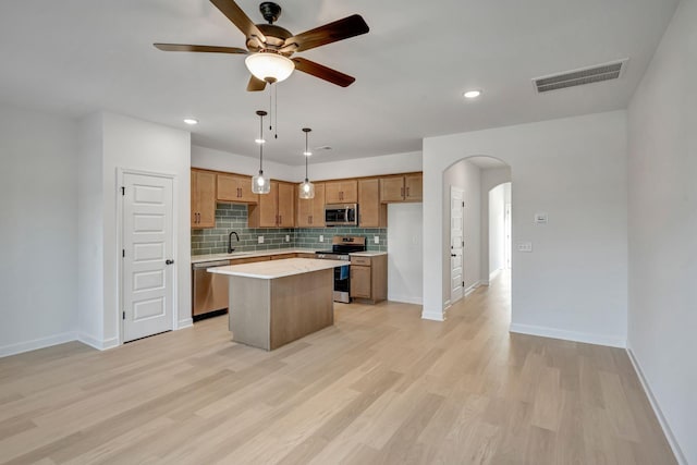 kitchen featuring backsplash, a kitchen island, light hardwood / wood-style floors, and appliances with stainless steel finishes