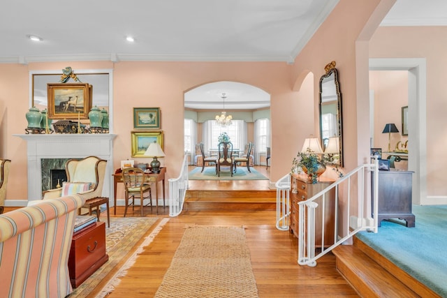 entrance foyer with light wood-type flooring, a chandelier, a premium fireplace, and ornamental molding