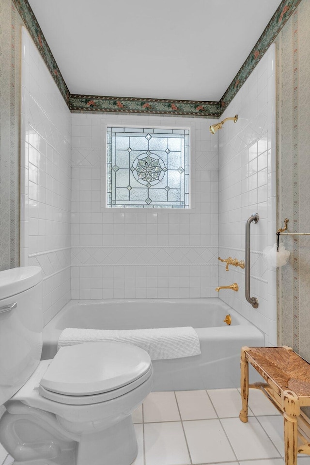 bathroom with toilet, tile patterned floors, and tiled shower / bath