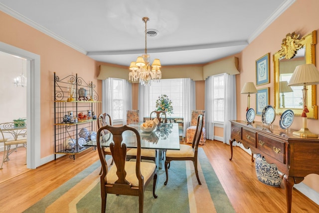 dining room with light wood-type flooring, an inviting chandelier, and crown molding