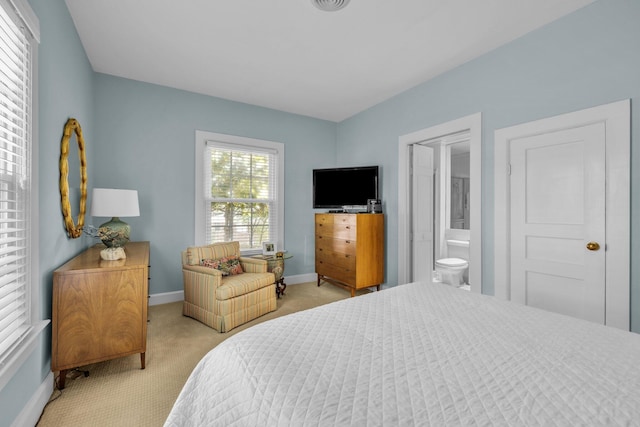 bedroom featuring light colored carpet and ensuite bathroom