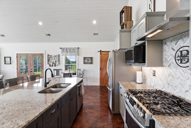 kitchen with decorative backsplash, appliances with stainless steel finishes, french doors, light stone countertops, and sink