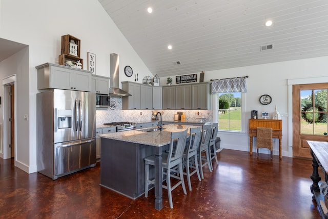 kitchen featuring wall chimney exhaust hood, stainless steel appliances, plenty of natural light, and tasteful backsplash