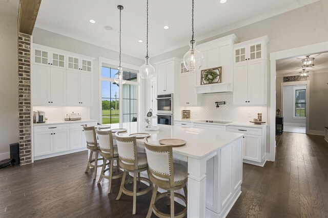 kitchen featuring a kitchen island with sink, a breakfast bar area, ornamental molding, and white cabinets