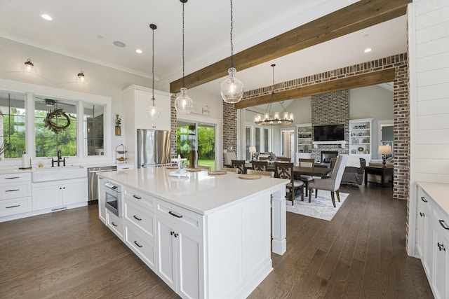 kitchen featuring sink, appliances with stainless steel finishes, a kitchen island, pendant lighting, and white cabinets