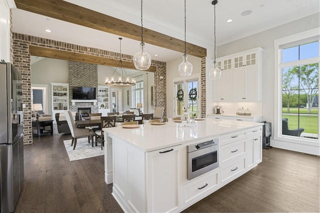 kitchen with appliances with stainless steel finishes, pendant lighting, a fireplace, white cabinetry, and a center island